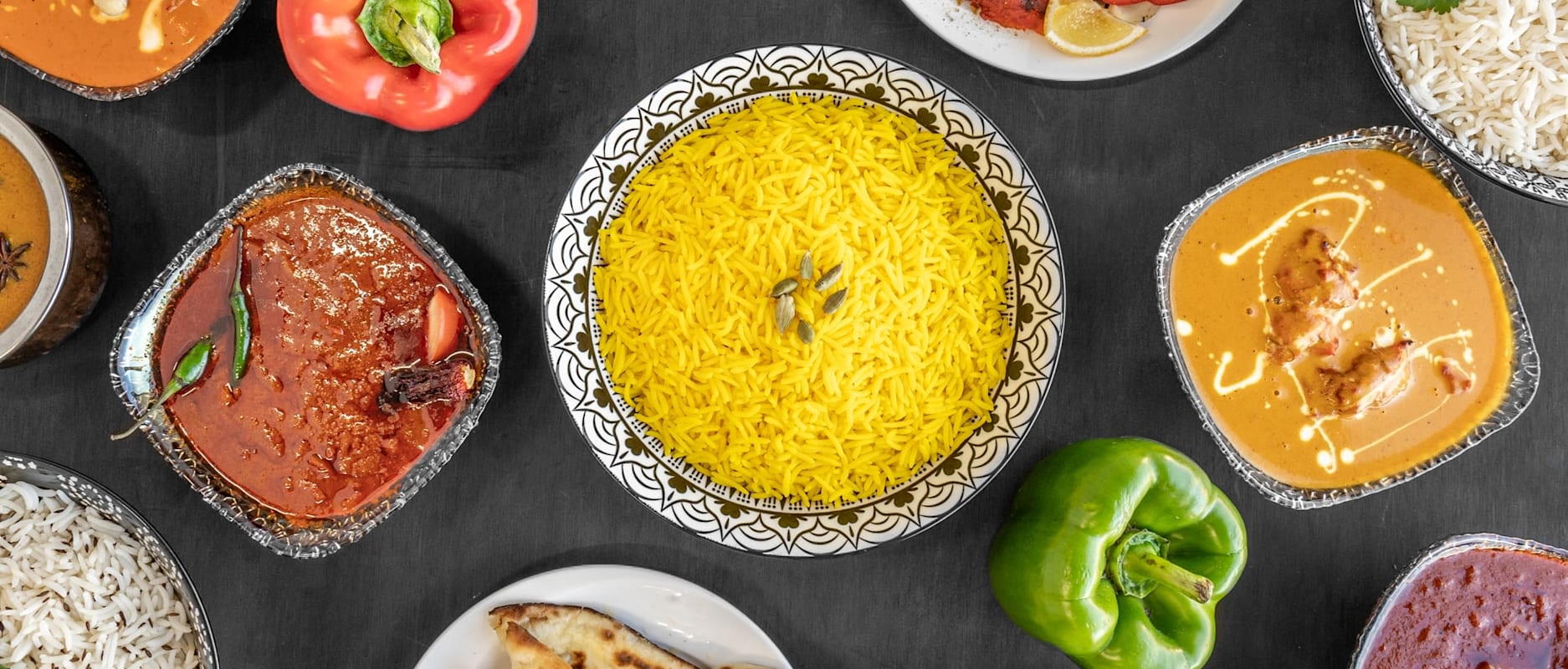 A top-down view of aromatic yellow Pilau rice garnished with cardamom pods, 
served on a patterned plate at MariGold restaurant in Kilmacolm 