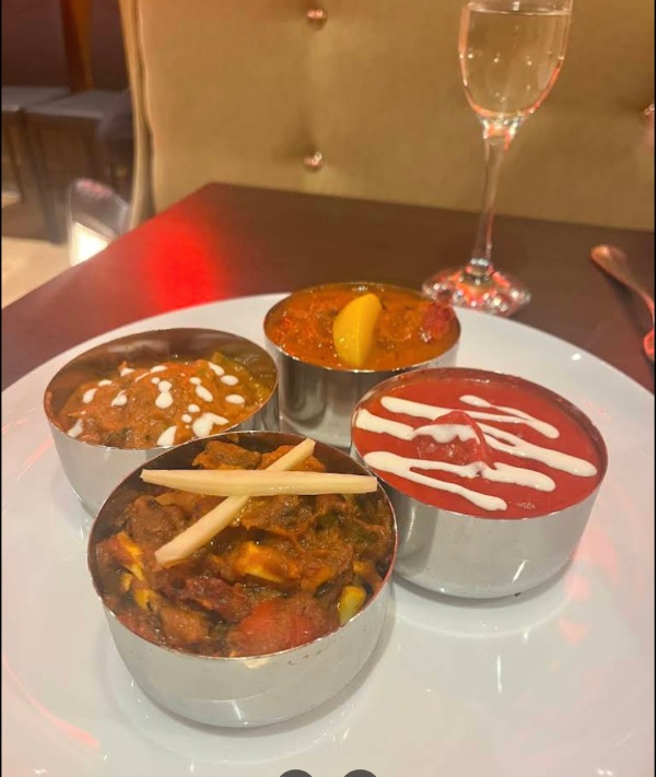 A selection of four different Indian curries served in small silver bowls on a 
white plate at MariGold, Kilmacolm. 